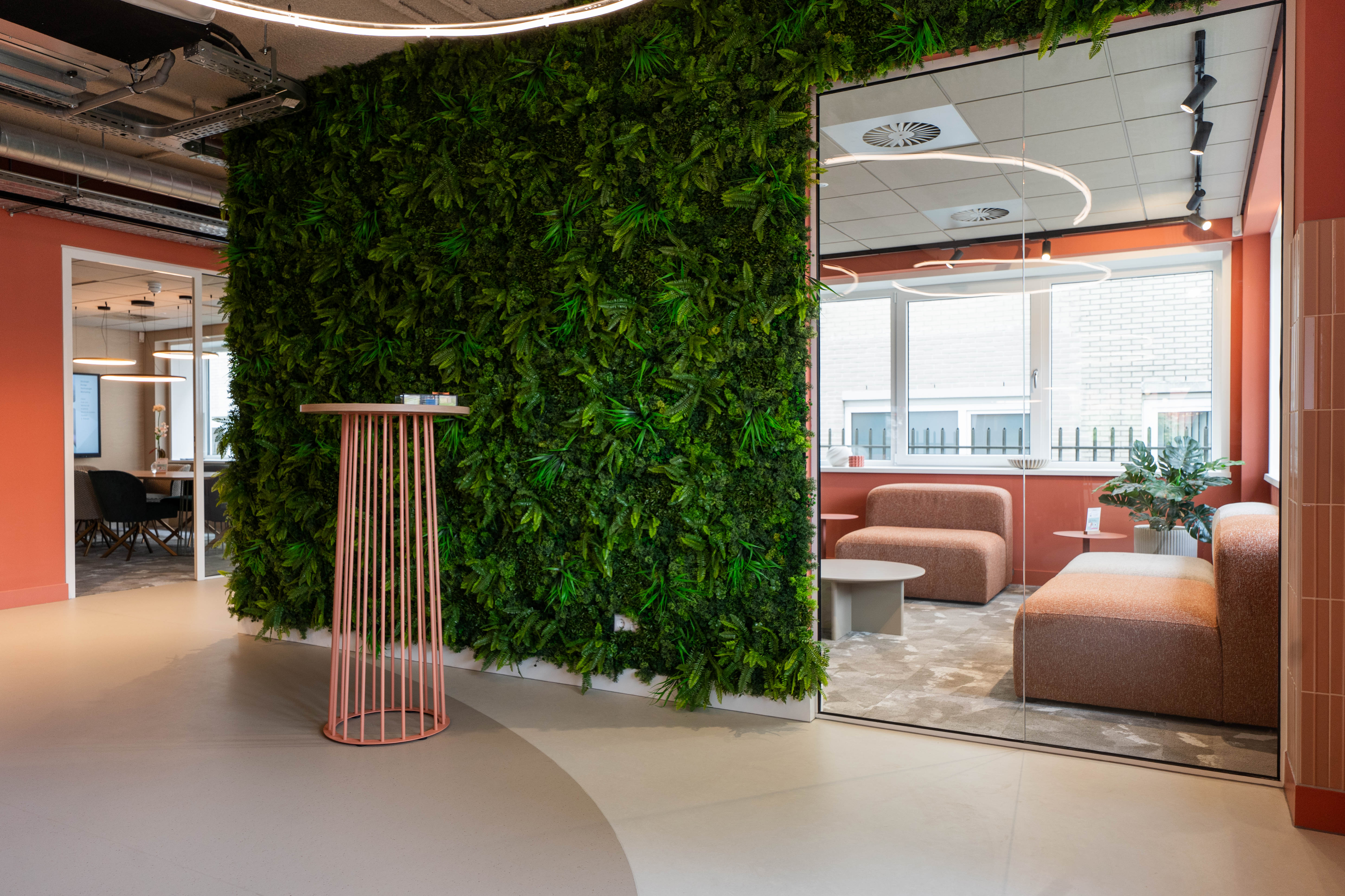 Ontvangstruimte bij Nedbase met een plantenwand en loungeruimte