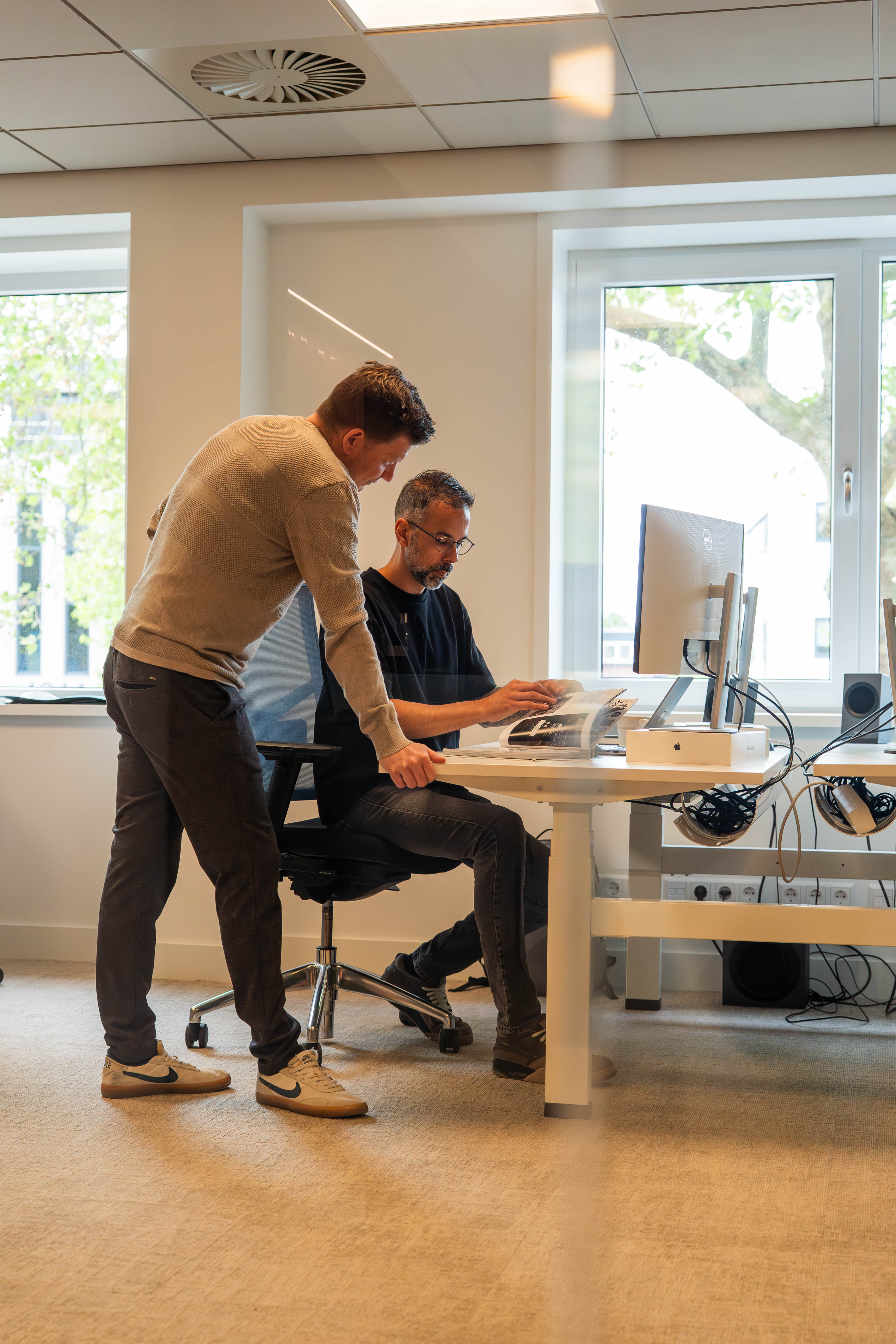 Twee collega's overleggen achter een bureau