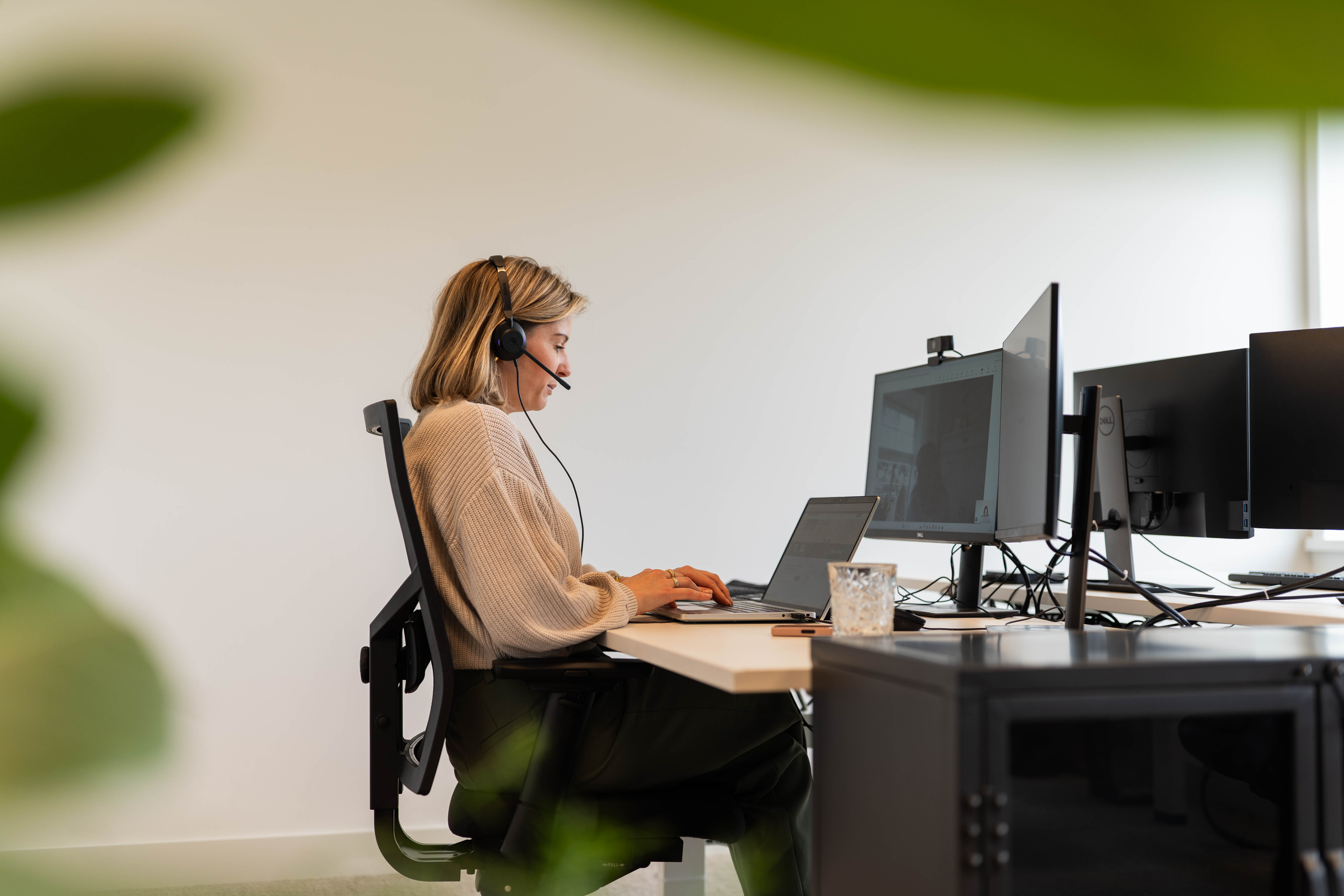 Iemand werkt geconcentreerd op een flexplek met koptelefoon